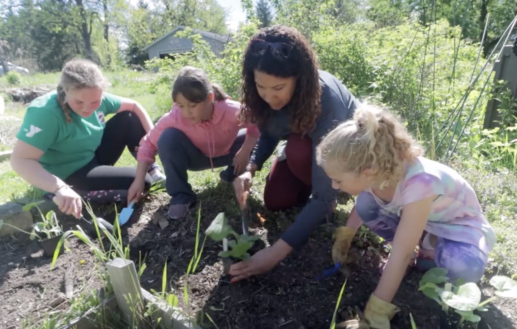 Adults planting garden with three children